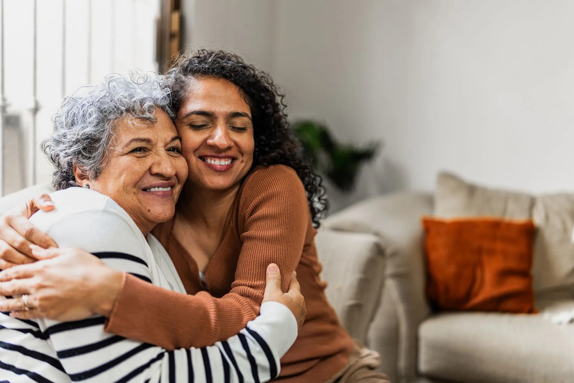 Mother and adult daughter laughing together at home, connected through clear conversation